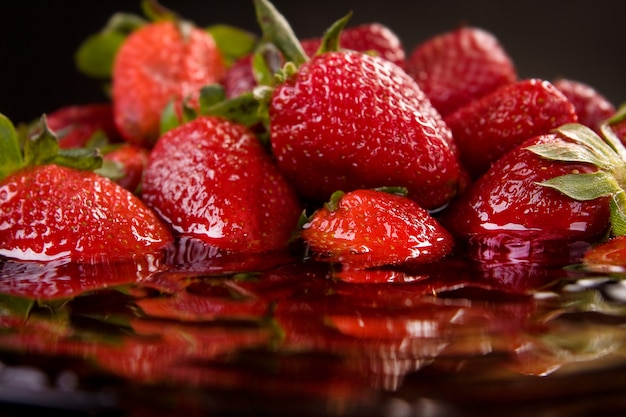 Foto closeup de morango em uma superfície líquida preta com reflexão