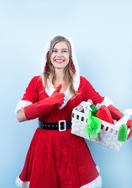 Closeup de mulher feliz caucasiana vestindo roupas de papai noel e luvas de limpeza segurando sprays de limpeza