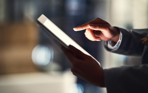 Closeup de mulher lendo notícias de mídia social em um tablet digital enquanto trabalhava até tarde em um escritório mulher profissional navegando on-line pesquisando planos e estratégias criativas para um projeto de negócios