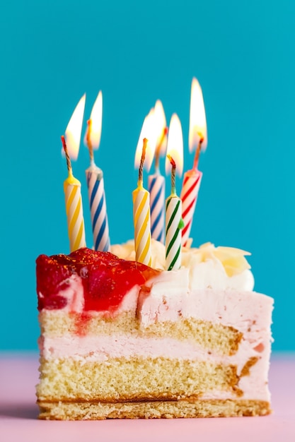 Closeup de pedaço de bolo de aniversário bonito saboroso apetitoso com muitas velas. conceito de feriado de aniversário.