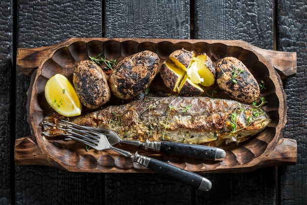 Closeup de peixe truta e batatas com manteiga e ervas