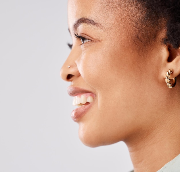 Closeup de perfil de mulher negra e sorriso de felicidade em um estúdio pensando e sentindo relaxar fundo branco isolado e rosto de modelo feliz com juventude e afro natural com empoderamento feminino e ideia