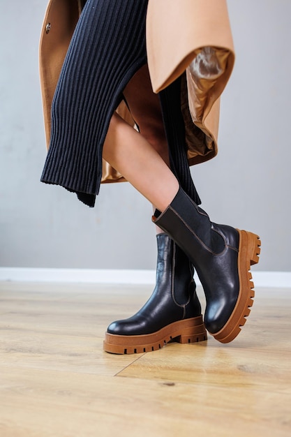 Closeup de pernas femininas em botas chelsea de couro preto, sapatos casuais de primavera confortáveis para mulheres, botas chelsea de primavera femininas pretas