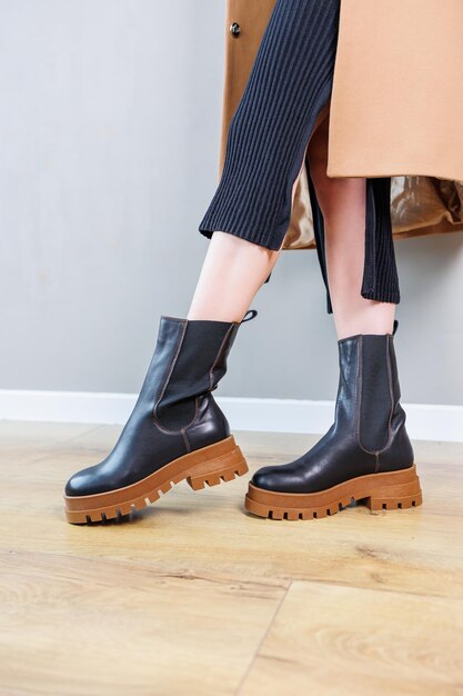 Closeup de pernas femininas em botas chelsea de couro preto, sapatos casuais de primavera confortáveis para mulheres, botas chelsea de primavera femininas pretas