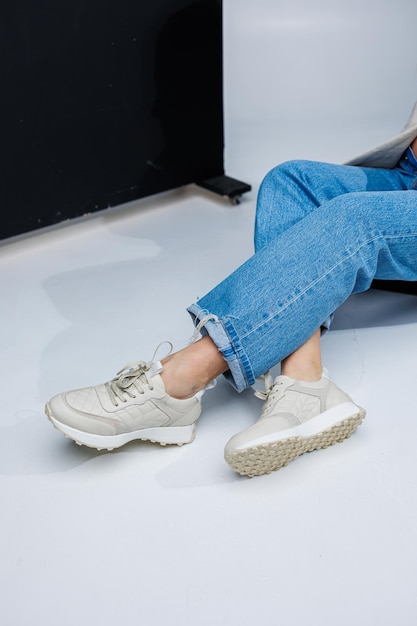 Closeup de pernas femininas em jeans e tênis branco estiloso Moda feminina casual Sapatos confortáveis para mulheres Sapatos confortáveis de verão para mulheres