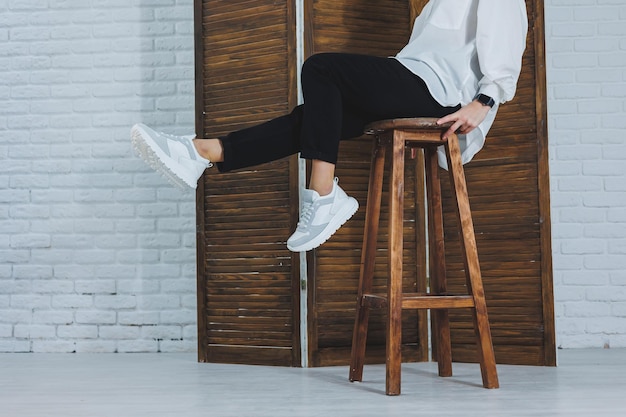 Closeup de pernas femininas em jeans pretos em elegantes tênis brancos de couro Mulher elegante em novos tênis Coleção sazonal moderna de tênis elegantes Moda feminina