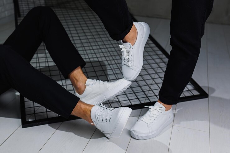 Foto closeup de pernas masculinas e femininas em calças pretas e tênis casuais brancos sapatos de couro masculinos e femininos de verão