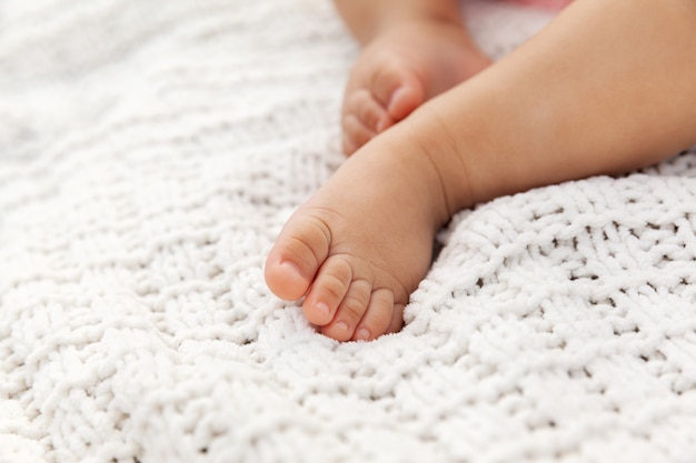 Closeup de pés de bebê adorável no cobertor de malha como pano de fundo em um foco seletivo