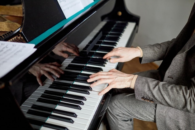 Closeup de pianista de terno tocando música clássica no piano na aula de música