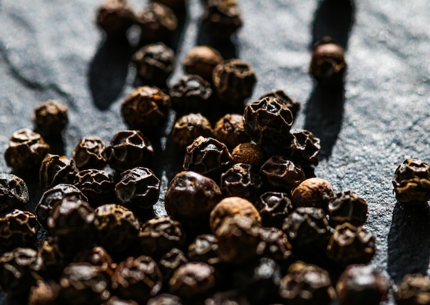 Closeup de pimenta preta em fundo de pedra de luxo como temperos de alimentos secos planos e ingredientes de receita