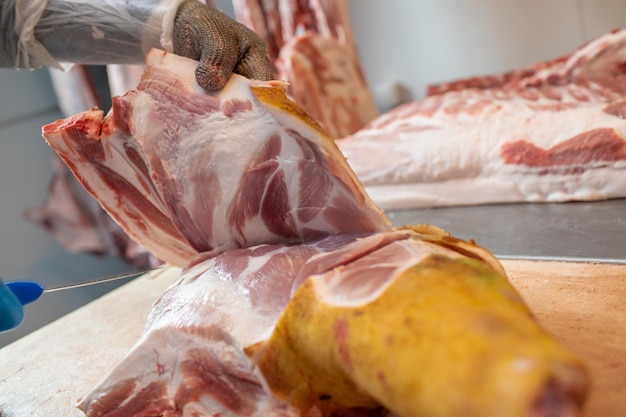 closeup de processamento de carne na indústria alimentícia o trabalhador corta armazenamento de porco cru na geladeira