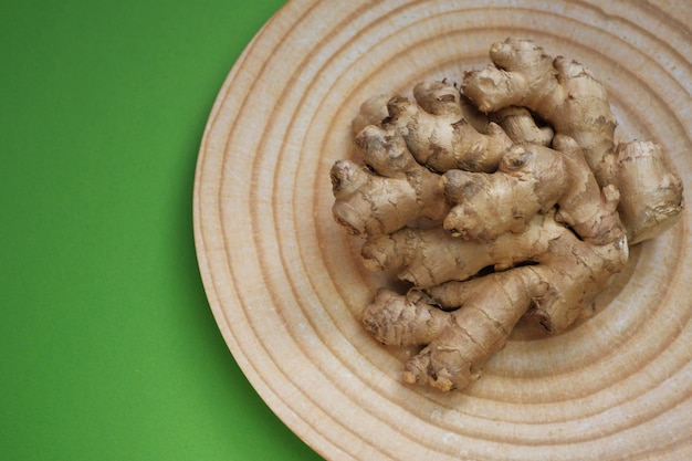 Closeup de raiz de gengibre em um prato redondo em uma parede brilhante Especiarias e vegetais orgânicos, bio saudáveis