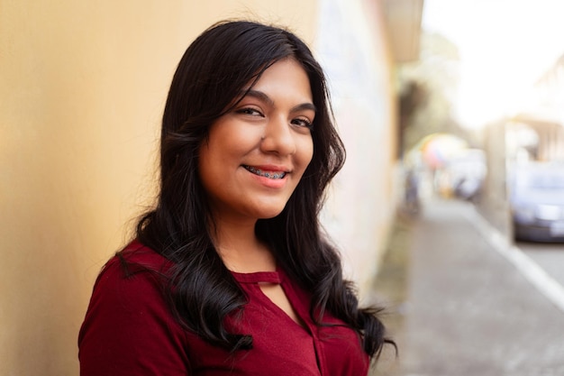 Closeup de retrato de jovem latino-americana sorrindo com colchetes sobre a cidade de rua