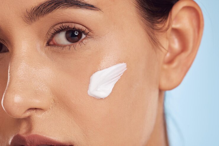 Foto closeup de retrato e mulher com dermatologia de creme e cuidados com a pele em um fundo de estúdio azul rosto de pessoa do sexo feminino e modelo com loção de cosméticos e beleza com creme estético e produto de luxo