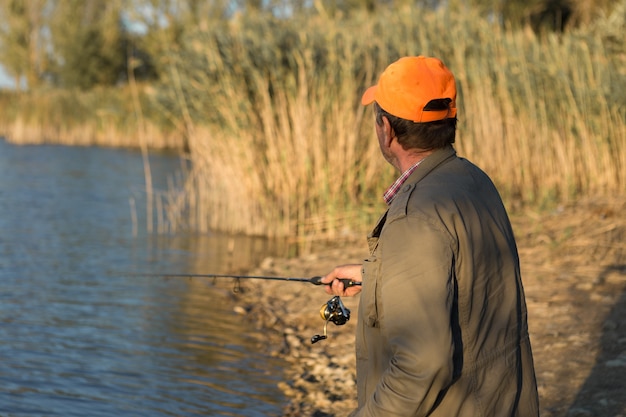 Foto closeup de roda de vara de pesca, homem pescando com um belo pôr do sol.