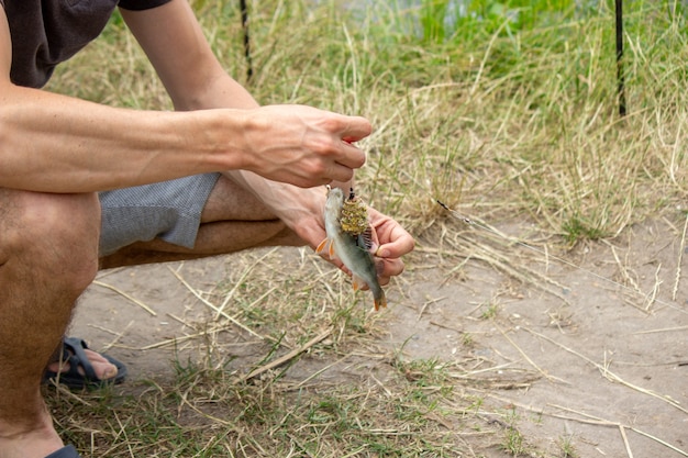 Closeup de roda de vara de pesca, homem pescando com um lindo nascer do sol atrás de si