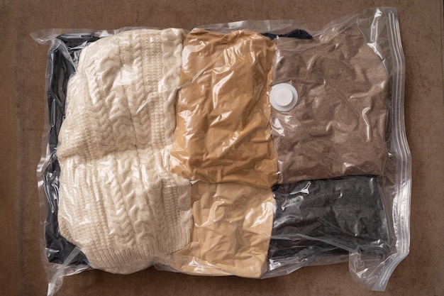 Closeup de saco transparente compactado com roupas de inverno para armazenamento sazonal Um conceito de economia de espaço em casa ou dobragem compacta para viagens