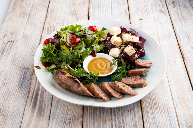 Closeup de salsicha de carne com salada de verduras e beterraba e molho