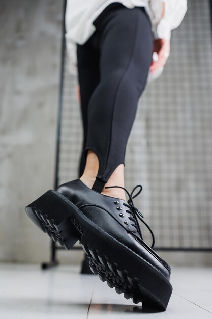 Closeup de sapatos de renda de couro preto nas pernas femininas em leggings pretas elegantes sapatos de outono femininos