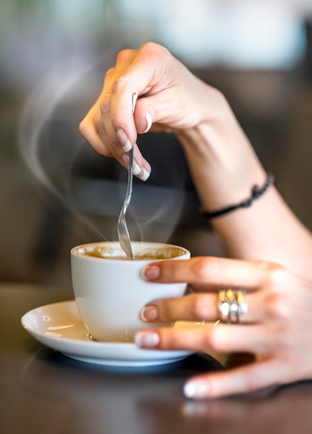 Closeup de senhora derramando o açúcar enquanto prepara a xícara de café quente