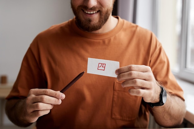 Closeup de sorridente jovem mostrando cartão de papel com hieróglifo escrito com marcador vermelho e exp