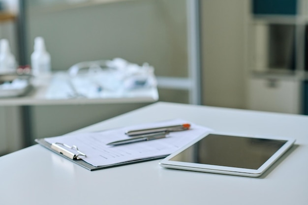 Closeup de tablet digital com cartão médico deitado na mesa do médico no escritório