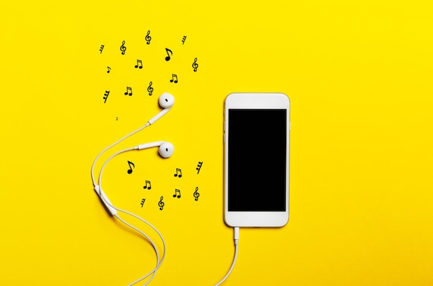 Foto closeup de telefone inteligente com fones de ouvido em um fundo amarelo ouvir música
