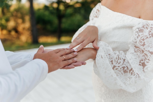 Closeup de tema de casamento segurando as mãos toques suaves de recém-casados