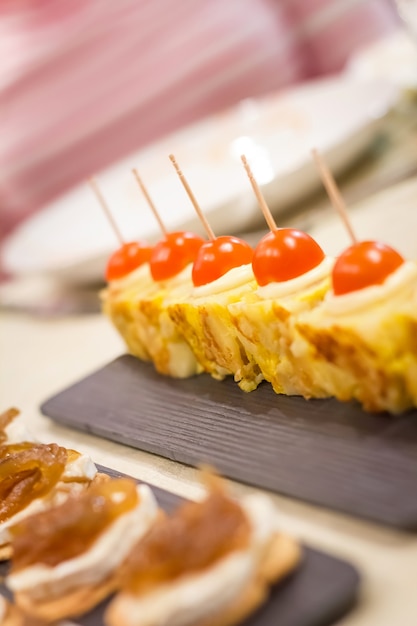 Closeup de típicos tapas de omelete espanhola e queijo com pinchos de cebola caramelizada em um bar