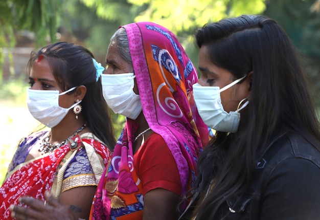 Closeup de três mulheres indianas usando máscaras, em pé ao ar livre