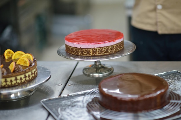 Closeup de um chef de pastelaria masculino concentrado decorando comida de bolo de sobremesa na cozinha