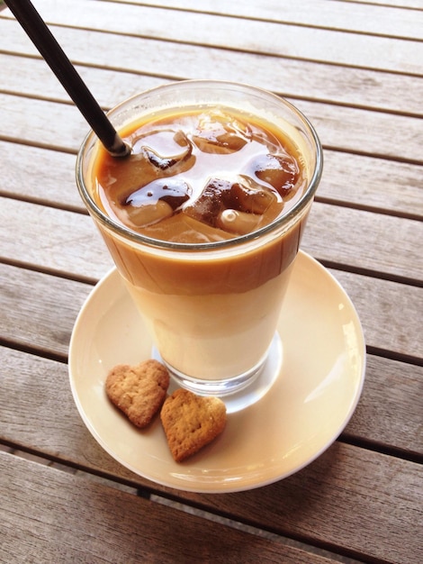 Closeup de um latte de café gelado com um canudo em uma mesa de madeira de um café