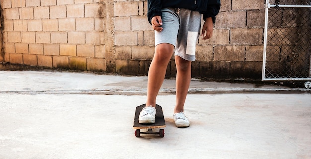Closeup de um menino praticando em pé em um skate no chão de concreto