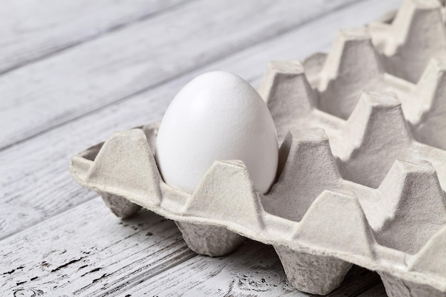 Closeup de um ovo em uma bandeja de caixa de ovos em fundo de madeira