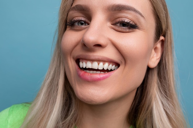 Closeup de uma jovem loira saudável com dentes retos em um fundo azul