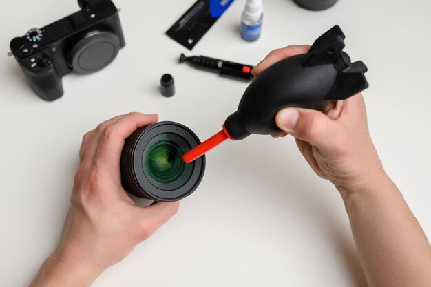 Foto closeup de uma mão limpando uma lente de câmera com um soprador de vista superior do equipamento fotográfico
