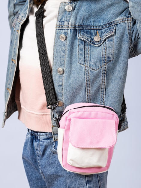 Closeup de uma menina em uma jaqueta jeans com uma linda bolsa de ombro no estúdio