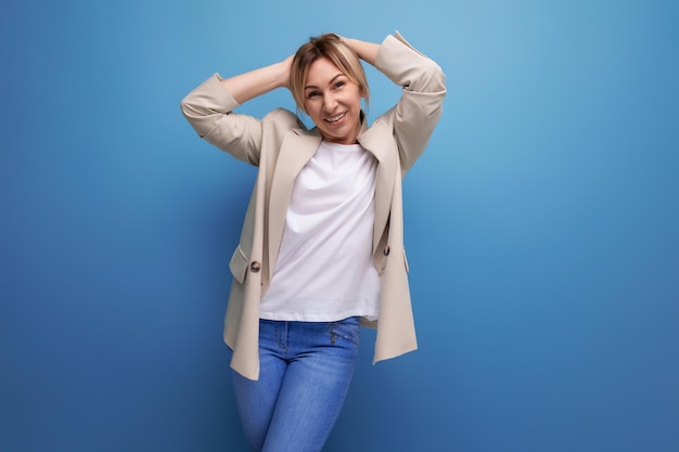 Closeup de uma mulher de negócios loira sorridente positiva em uma jaqueta bem sucedida no trabalho no fundo