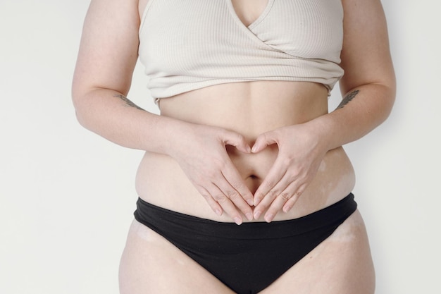 Closeup de uma mulher natural em cueca, criando uma forma de coração em seus quadris.