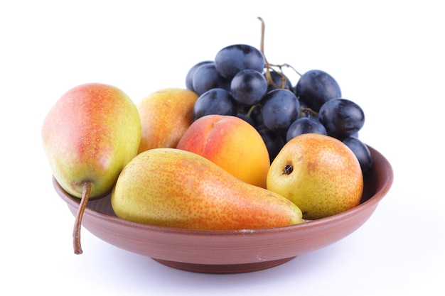 Closeup de uvas e peras coloridas em uma placa de barro Cachos de uvas e peras isoladas em fundo branco