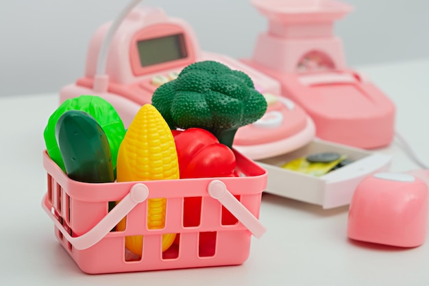 Closeup de vegetais de plástico de brinquedo infantil em cesta rosa loja de brinquedos para crianças entrega de supermercado on-line