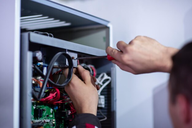 Closeup do engenheiro eletricista trabalhando com fios de cabos elétricos da moderna caixa de interruptores de fusíveis. Equipamento elétrico ajustando nova fiação de tensão
