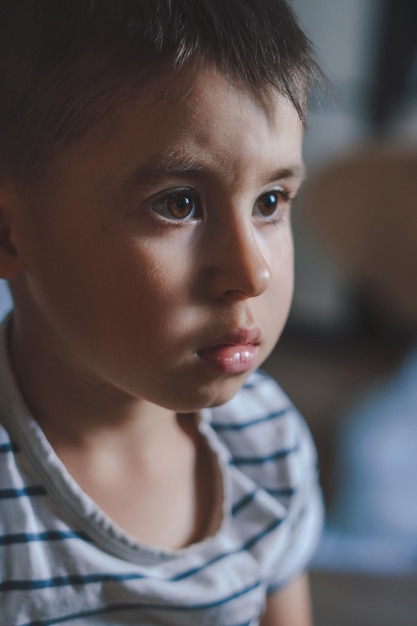 Closeup do rosto de um menino olhando fixamente para algo na casa Conceito de infância Mudança natural do estado emocional