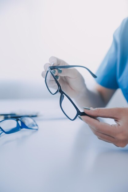 Closeup de una doctora asiática hablando con un paciente anciano mostrando el modelo del globo ocular y explicando la enfermedad ocular en el hospital