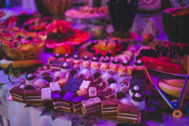 Foto closeup de dulces y bocadillos en la mesa bajo luces de color durante un evento en un restaurante