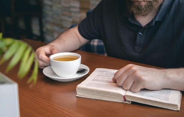 Closeup eine Tasse Tee und ein Buch in männlichen Händen