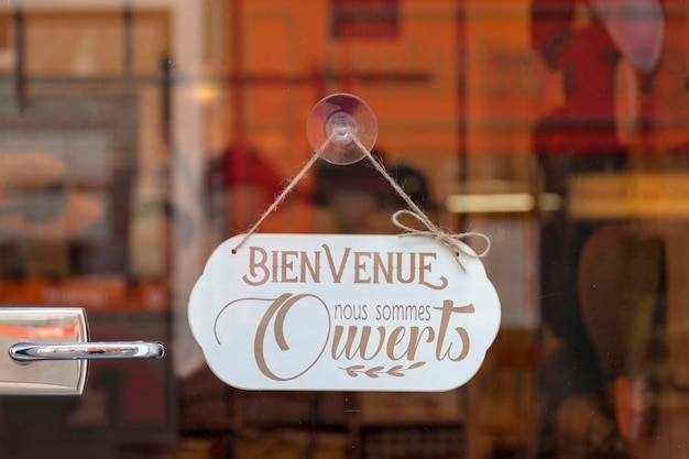 Foto closeup em uma placa dizendo em francês bienvenue nous sommes ouverts meanung em inglês bem-vindo, estamos abertos