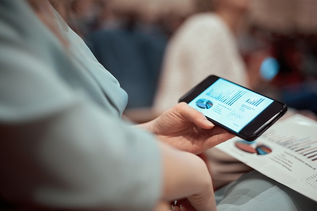 Closeup empresária com um smartphone sentada na sala de conferências