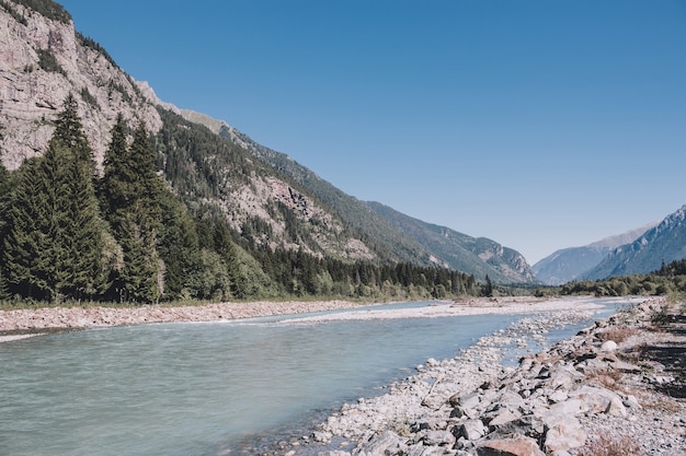 Closeup exibição de cenas de rio nas montanhas do Parque Nacional Dombai, Cáucaso, Rússia, Europa. Paisagem de verão, clima ensolarado, céu azul dramático e dia ensolarado
