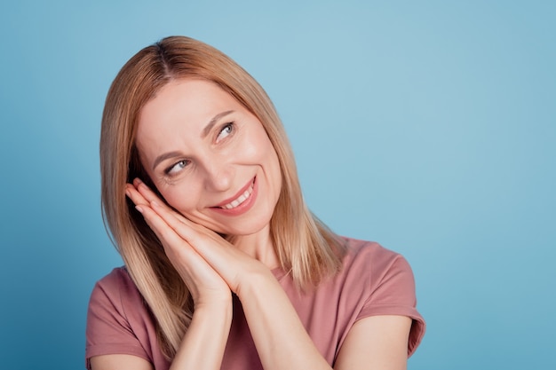 Closeup foto de mulher atraente feliz sorriso positivo com as mãos tocando a bochecha olhar espaço vazio isolado fundo de cor azul